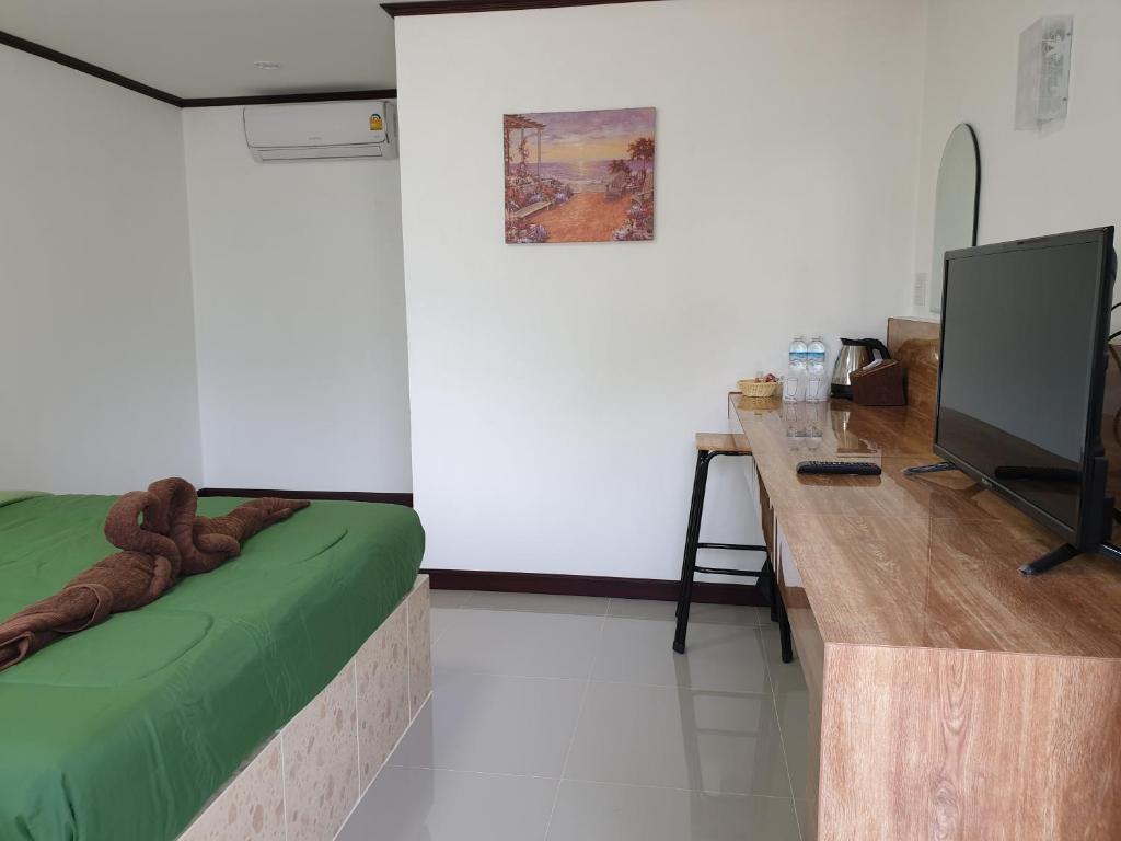 a room with a bed and a desk with a television at Rung Inn Homestay in Ranong