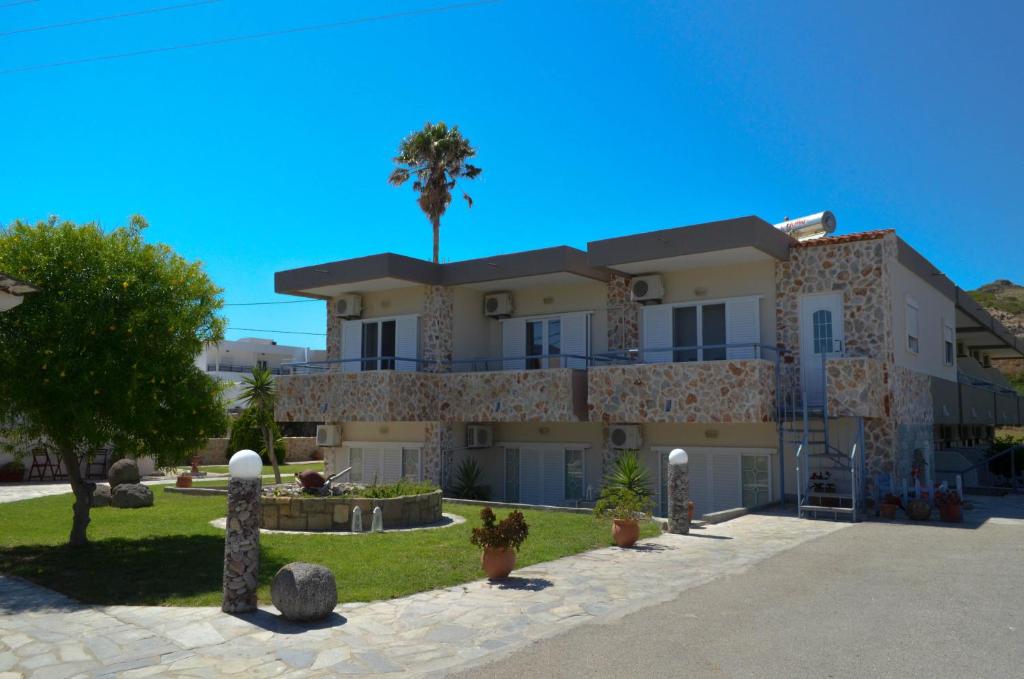 ein großes Gebäude mit einer Palme im Hintergrund in der Unterkunft Sevi Apartments in Kefalos