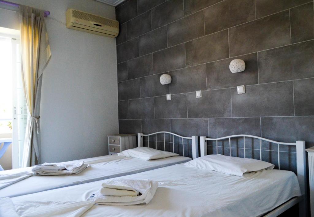 2 łóżka w pokoju ze ścianą wyłożoną kafelkami w obiekcie Sevi Apartments w mieście Kefalos