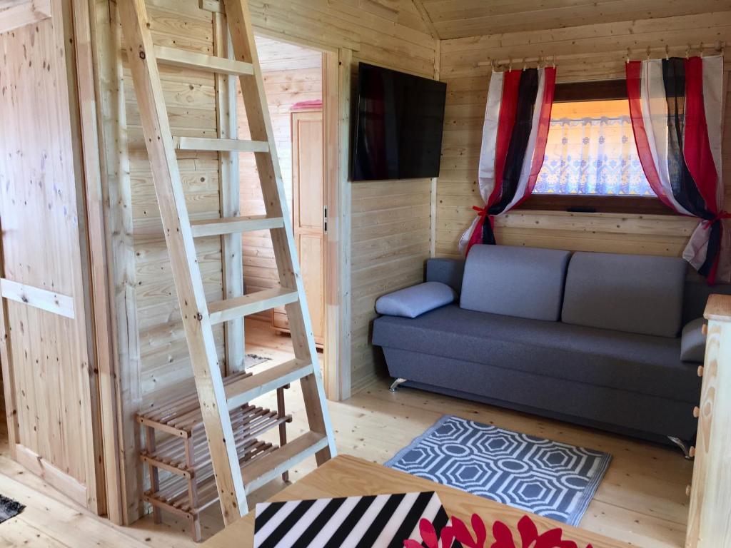 a tiny house with a couch and a ladder at Domki Magnolia in Rusinowo