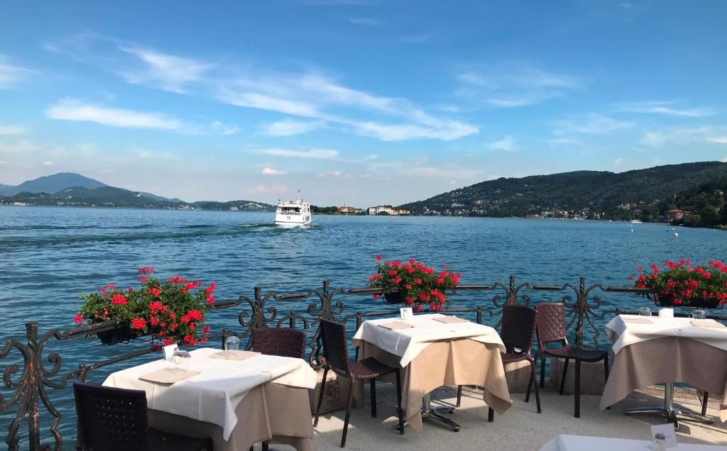 two tables and chairs with a boat in the water at Hotel Eden in Baveno