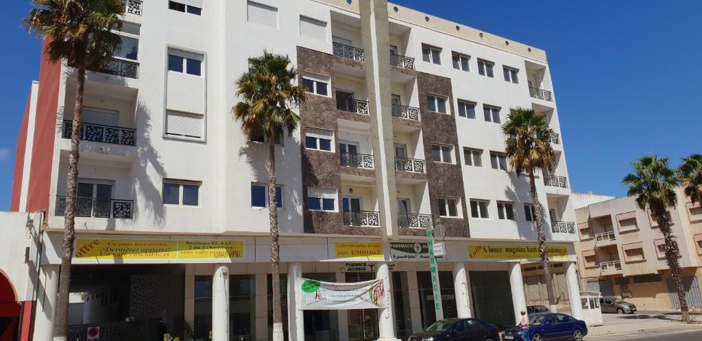 un edificio blanco con palmeras delante en 356 Avenue Bir Anzarane Appartement, en El Jadida