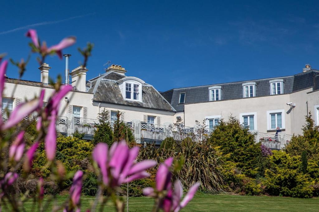 a large white house with pink flowers in the foreground at Cliffden Hotel in Teignmouth