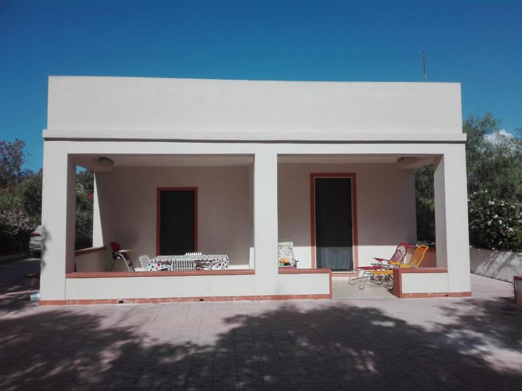 een wit huis met een patio met een tafel en stoelen bij Villa Simone in Pachino
