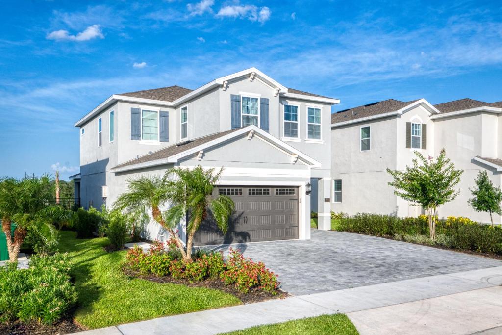 a large white house with a garage at Charming Home by Rentyl Near Disney with Private Pool, Game Room & Resort Amenities - 7489M in Orlando