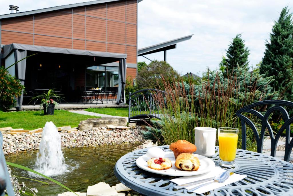 uma mesa com um prato de comida e um copo de sumo de laranja em Le Fabreville Motel & Suites em Laval