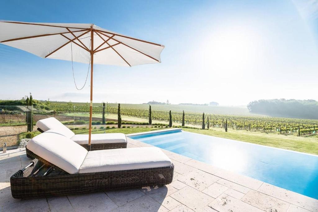 Pellegrue的住宿－Luxury French Stone Country House，游泳池旁带遮阳伞的椅子
