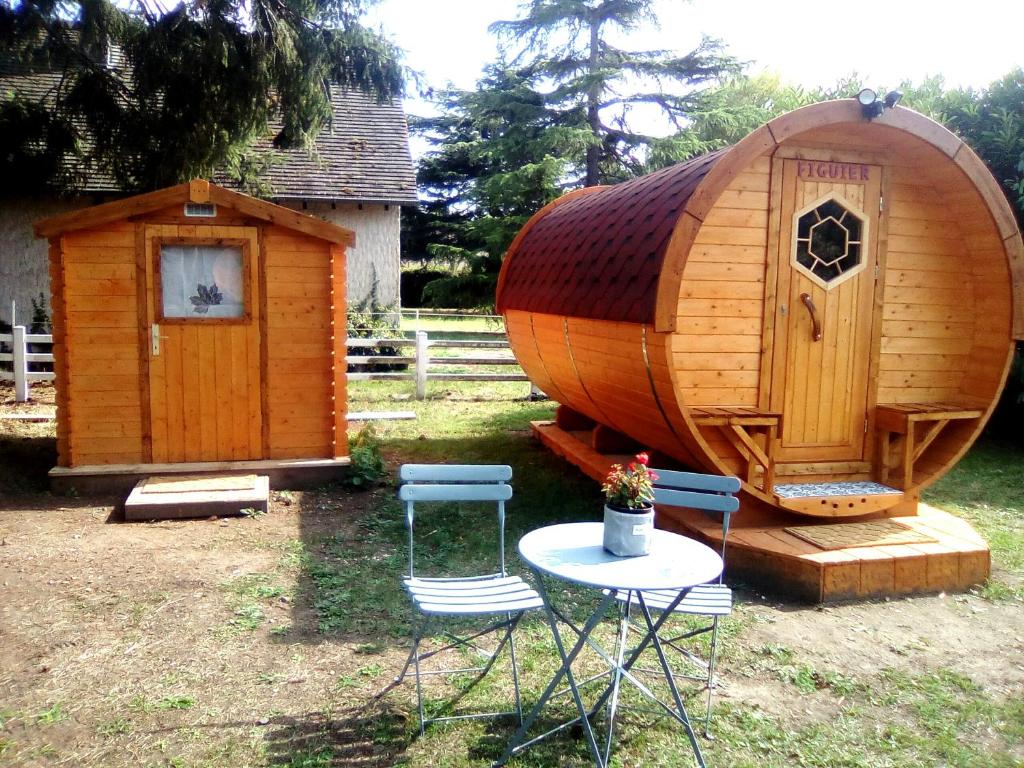 a large wooden cabin with two chairs and a table at LES TONNEAUX DE L'EURE LOGEMENT INSOLITE in Neuilly