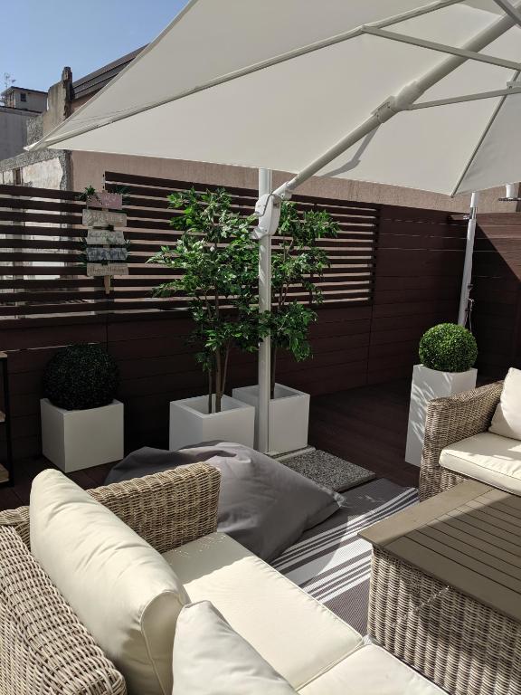 a patio with chairs and an umbrella and plants at EXCELSIOR 10 - Luxury apartment in Grado