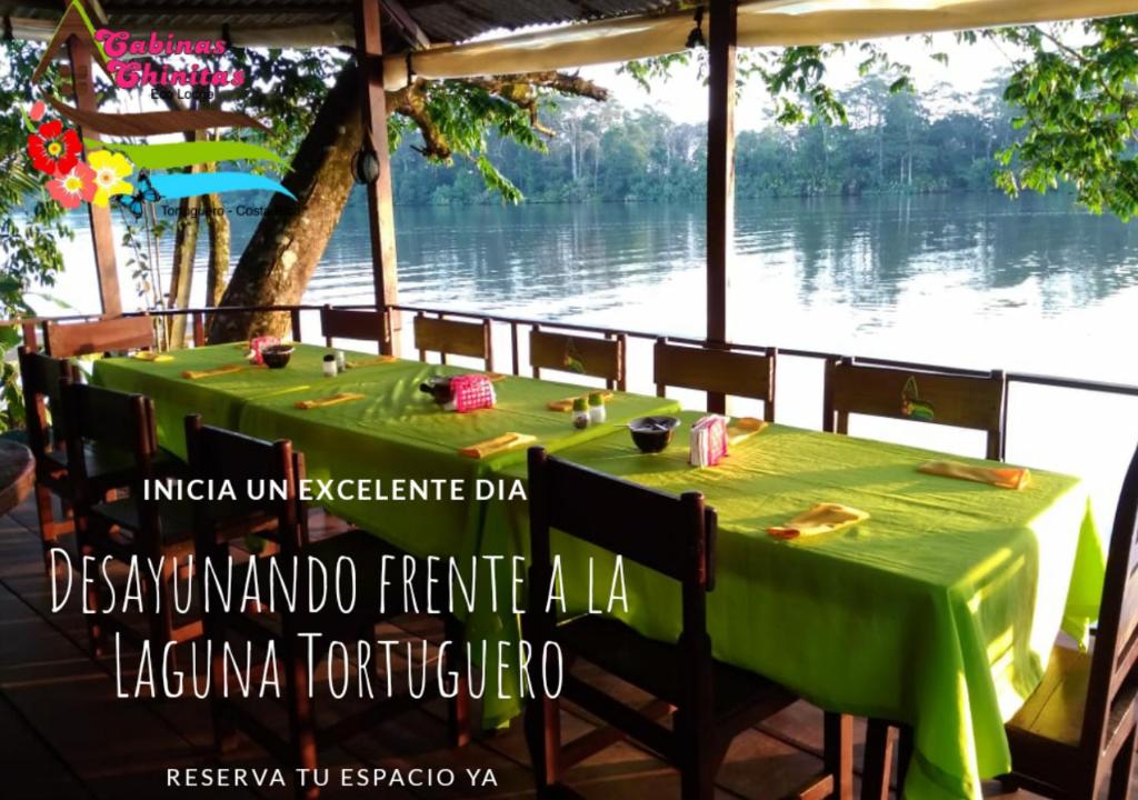 a green table with chairs in front of a river at Chinitas Eco Lodge in Tortuguero