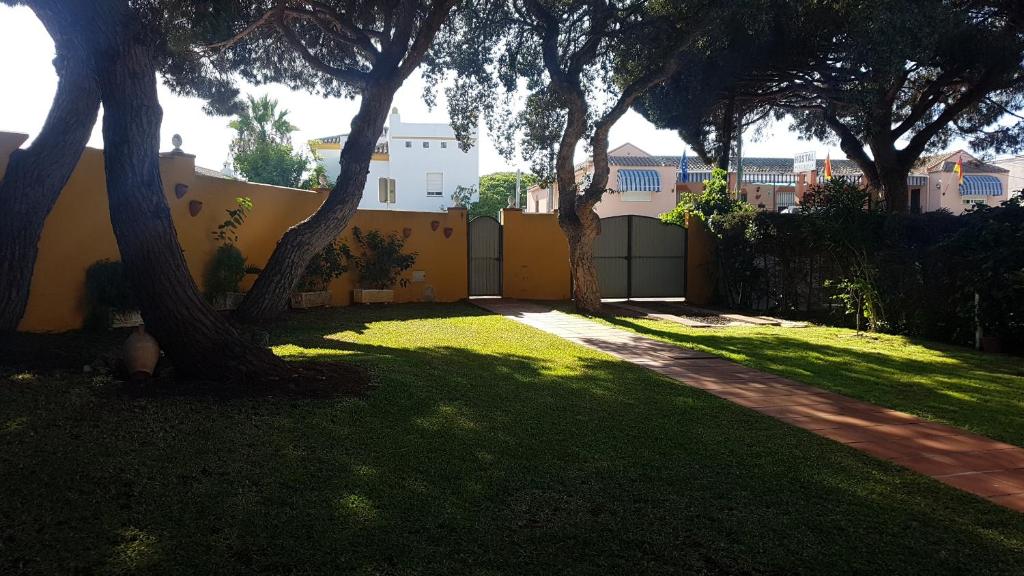 un patio con árboles y una valla amarilla en Chalet la barrosa a 800 mts playa, en Chiclana de la Frontera