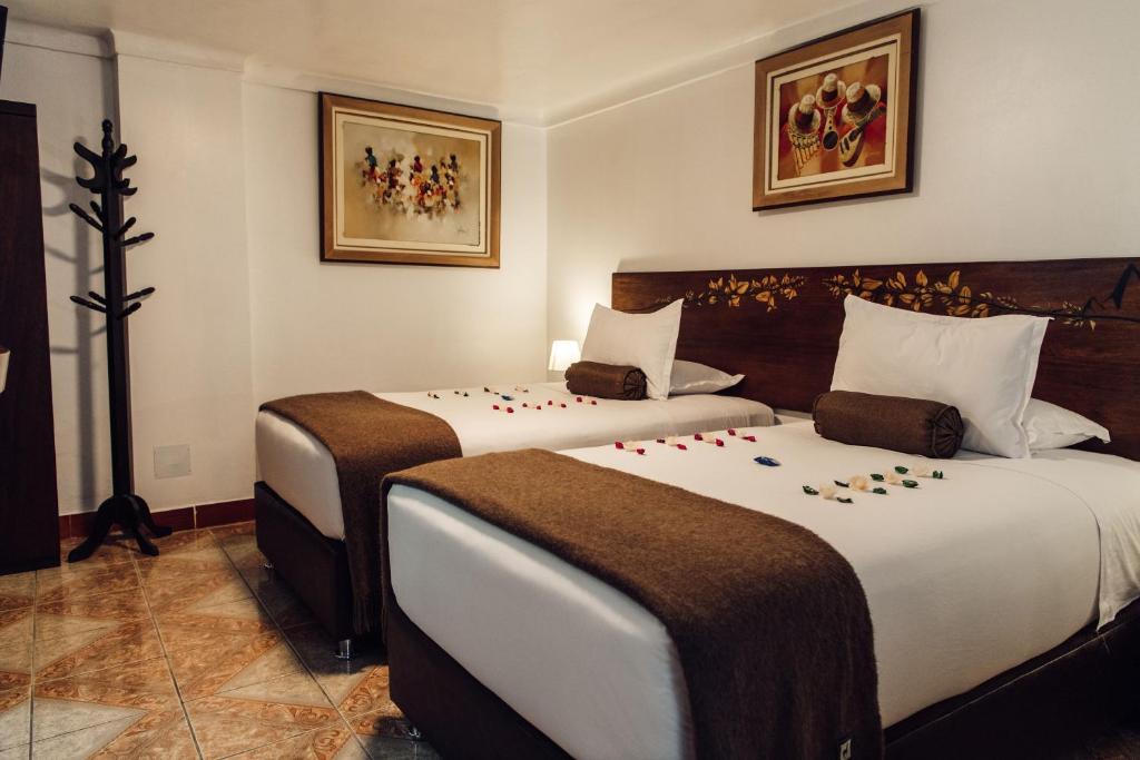 two beds in a hotel room with flowers on them at Hotel Retama Machupicchu in Machu Picchu