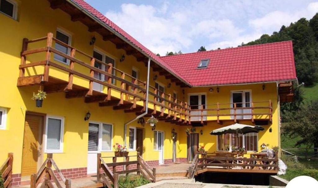 a large yellow building with a deck and tables at American Dream in Şimon