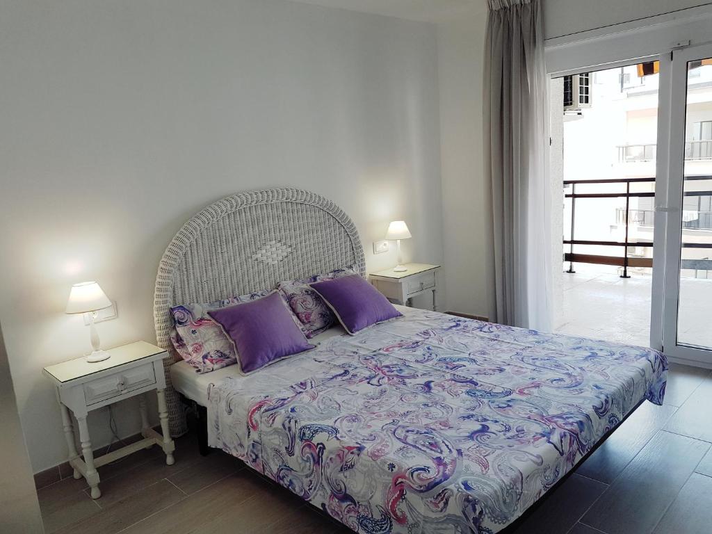 una camera da letto con un letto con cuscini viola e una finestra di Holiday apartment Salou a Salou