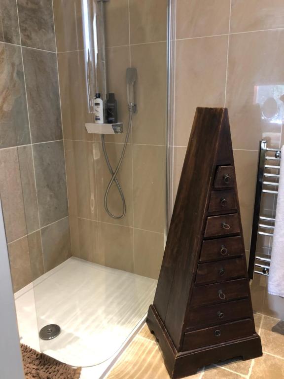 a bathroom with a shower with a wooden dresser at Belmont House Boutique - the Kingsley collection in Berwick-Upon-Tweed