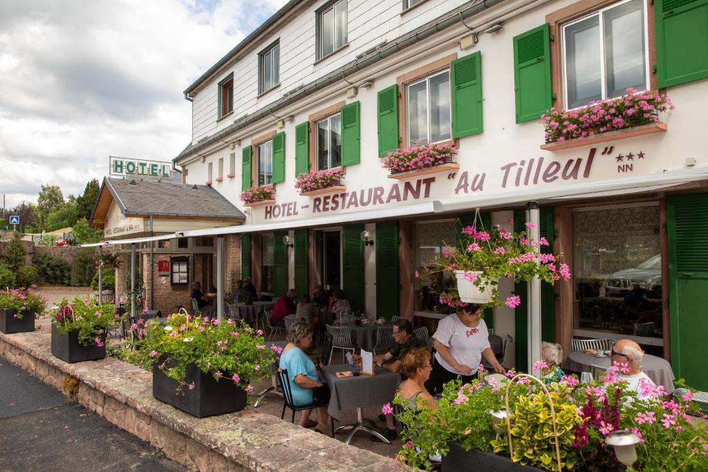 un groupe de personnes assis à l'extérieur d'un restaurant dans l'établissement Hôtel Restaurant et Spa Au Tilleul, à Labaroche