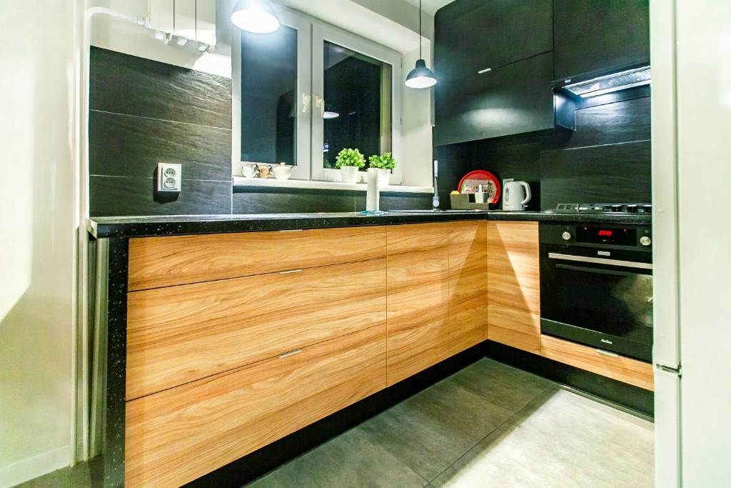una cocina con armarios de madera y electrodomésticos negros en JULIUSZ, en Sandomierz