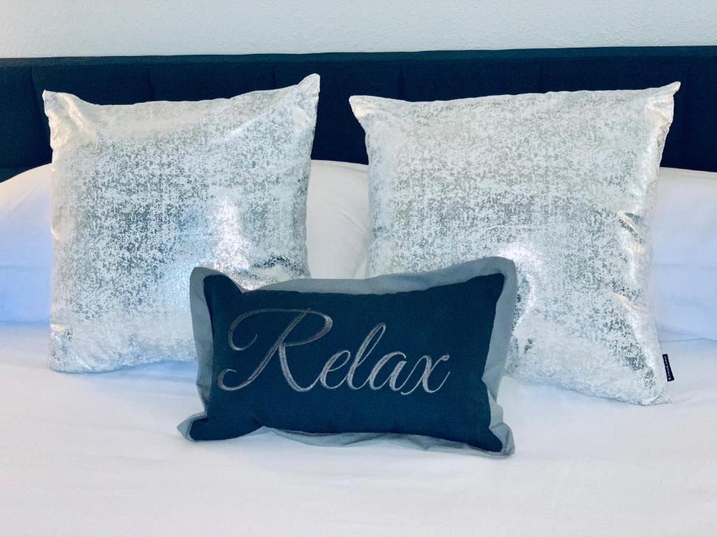 duas almofadas e uma almofada com a palavra relaxar numa cama em Bayside Retreat em Ruskin