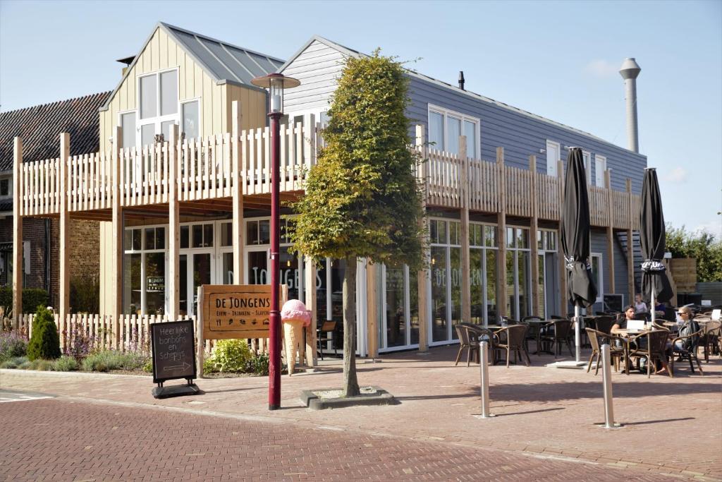 a building with a tree in front of it at De Jongens in Rockanje