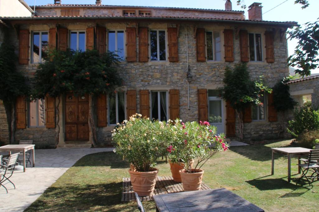 uma velha casa de pedra com flores em frente em Les Tilleuls em Saint-Georges-de-Luzençon