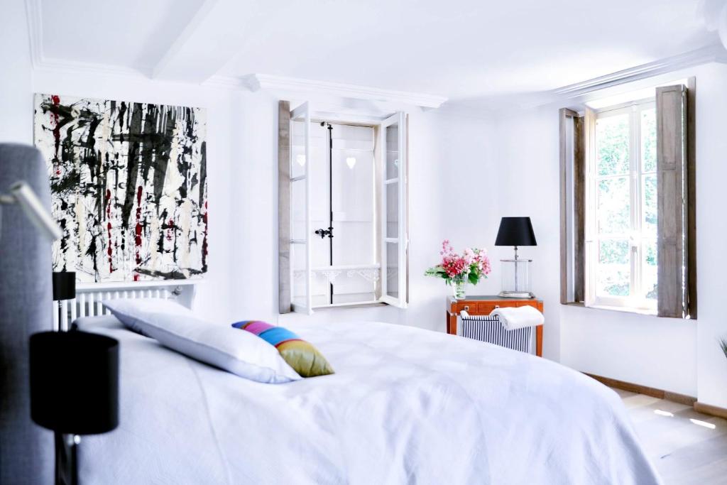 a white bedroom with a large white bed and windows at GLYCINES COUNTRY GUESTHOUSE in Goupillières