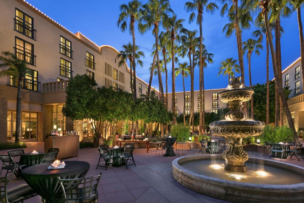 un patio con una fuente, mesas y palmeras en Tempe Mission Palms, a Destination by Hyatt Hotel, en Tempe