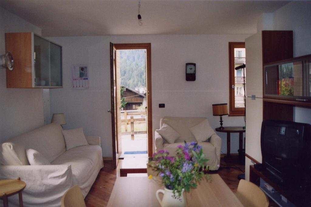 uma sala de estar com dois sofás brancos e uma mesa em Casa bianca em San Vito di Cadore