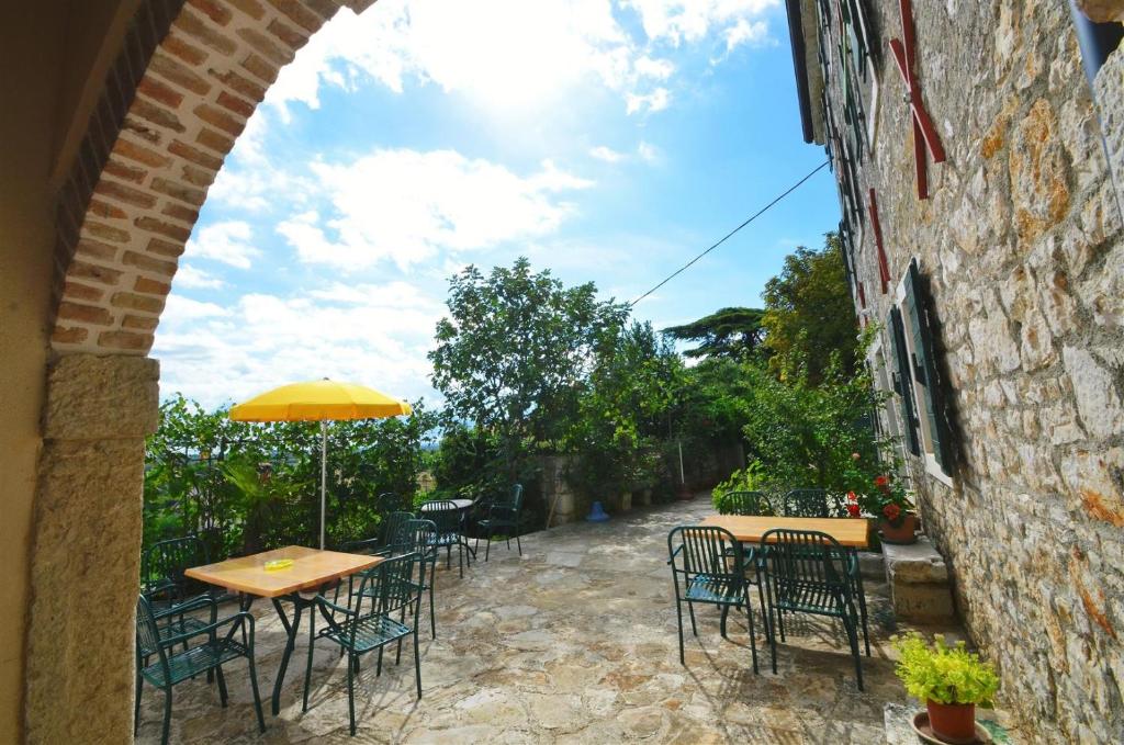 an outdoor patio with tables and chairs and an umbrella at Villa Visnjan Residence 2 in Višnjan