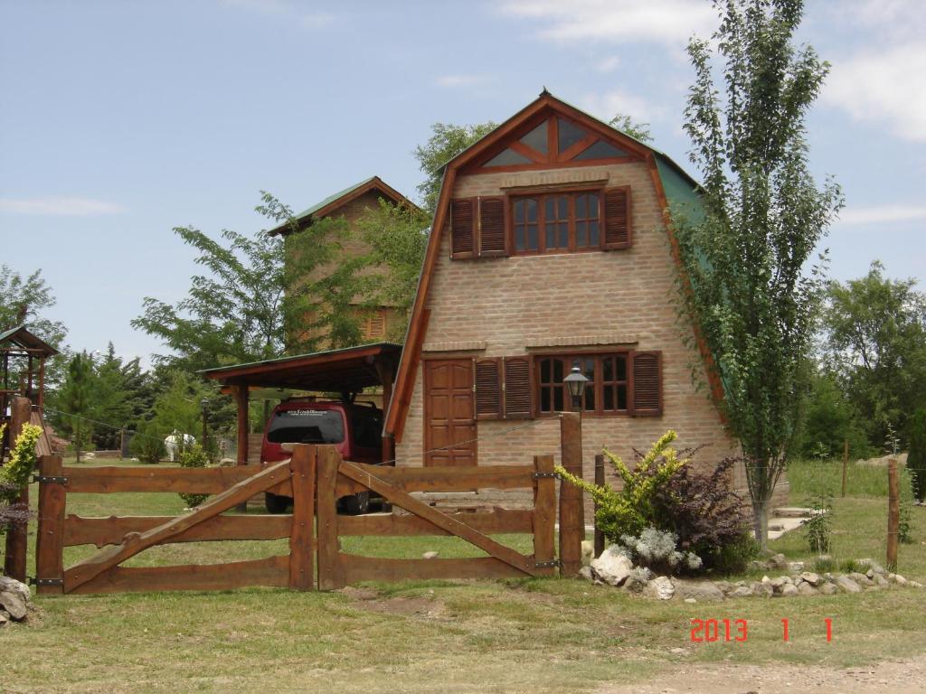 a house with a fence in front of it at Cabañas Ecos del Rio in Los Reartes