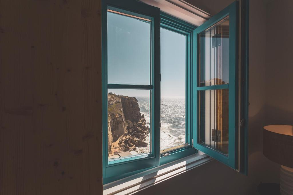 an open window with a view of the ocean at Azenhas do Mar West Coast Design and Surf Villas in Sintra