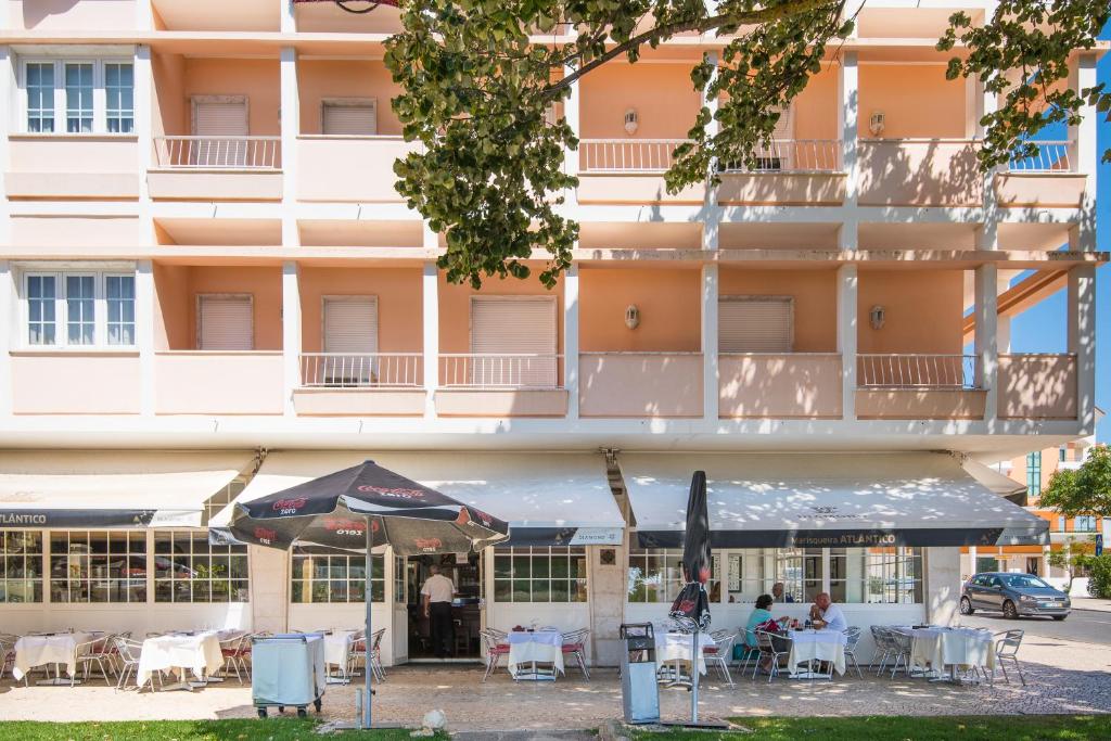 a hotel with tables and chairs in front of a building at Atlantic Waves Accommodation ~ Carcavelos Beach in Carcavelos