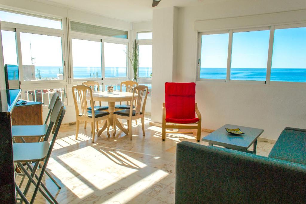 een woonkamer met een tafel en stoelen en de oceaan bij Magnifique vue à 100m de la plage in Benalmádena