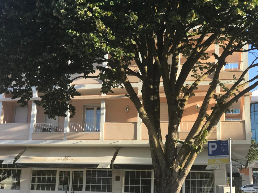 a white building with a parking sign in front of a tree at Atlantic Waves Accommodation in Carcavelos