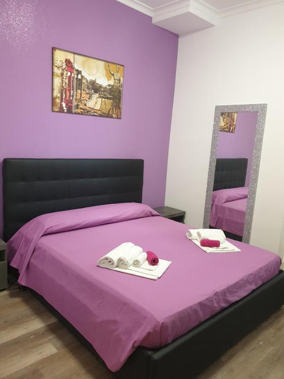 ein lila Schlafzimmer mit einem Bett und einem Spiegel in der Unterkunft B&B Da Ponticello in Rom