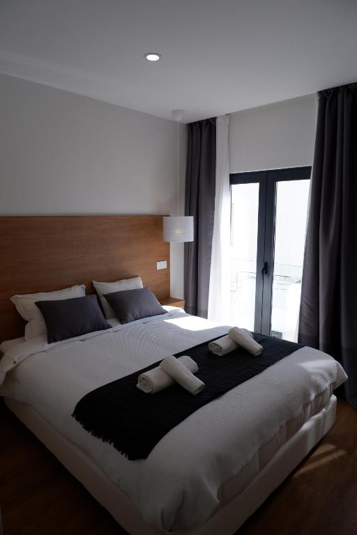 a large bed in a bedroom with a large window at VI MAR - GUEST HOUSE in Lagos