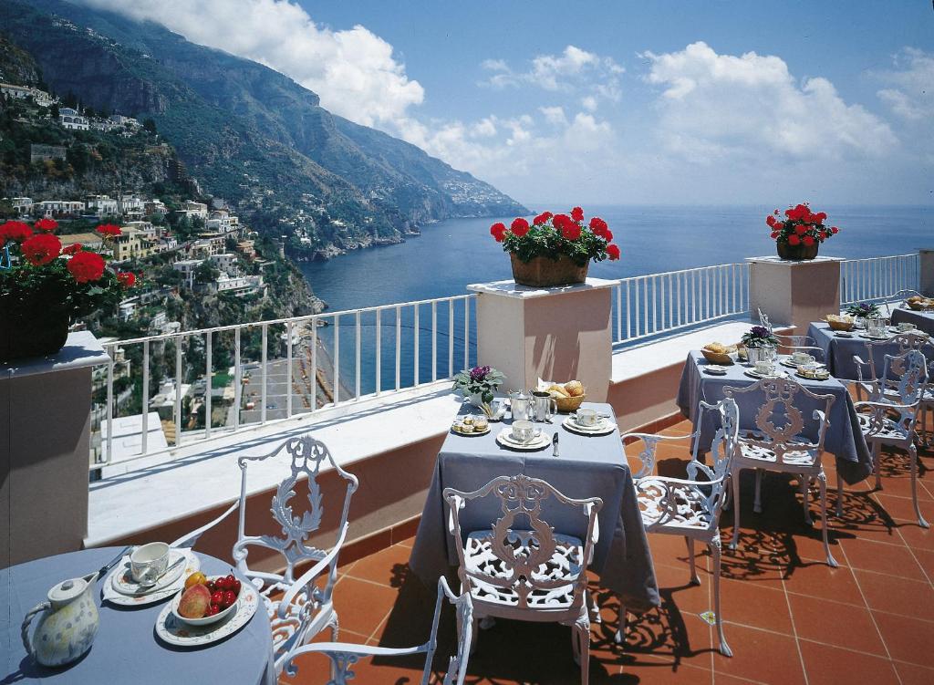 a balcony with tables and chairs with a view of the ocean at Hotel Casa Albertina in Positano