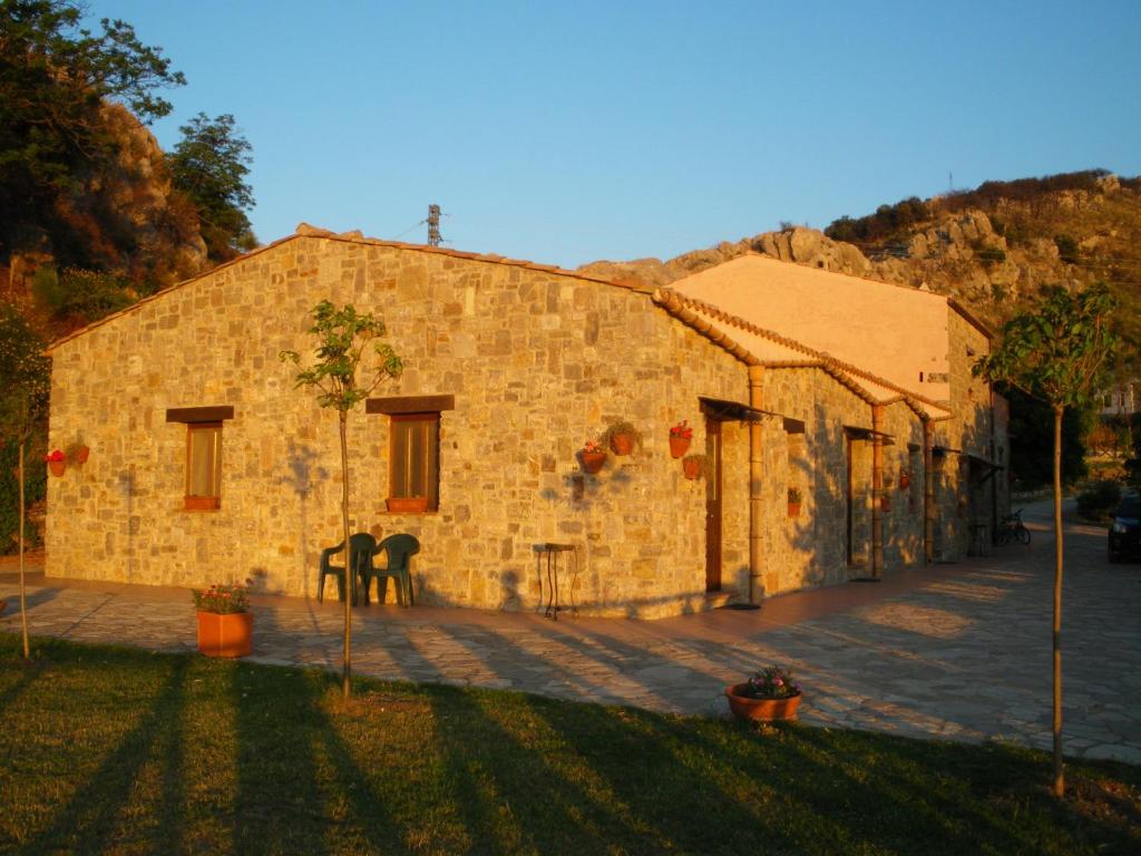 a stone building with a grass yard in front of it at Mandra Chiusilla in Collesano