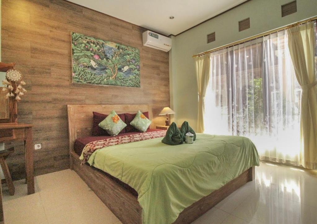 a bedroom with a bed with a green blanket and a window at Aurora House in Ubud