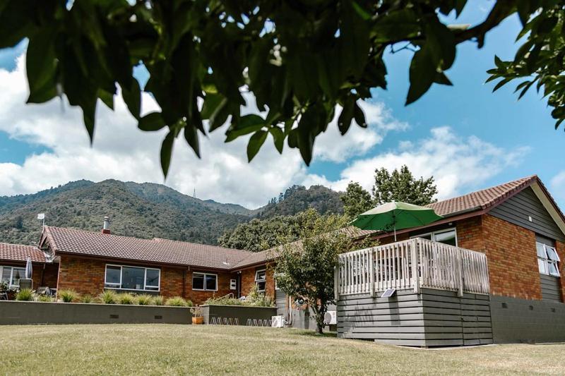 una casa de ladrillo con un paraguas verde delante de ella en The Nunnery, en Te Aroha