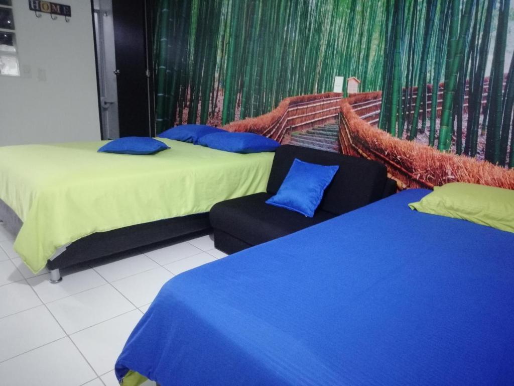 2 camas con almohadas azules y una silla en una habitación en APARTA ESTUDIO 7051 en Medellín