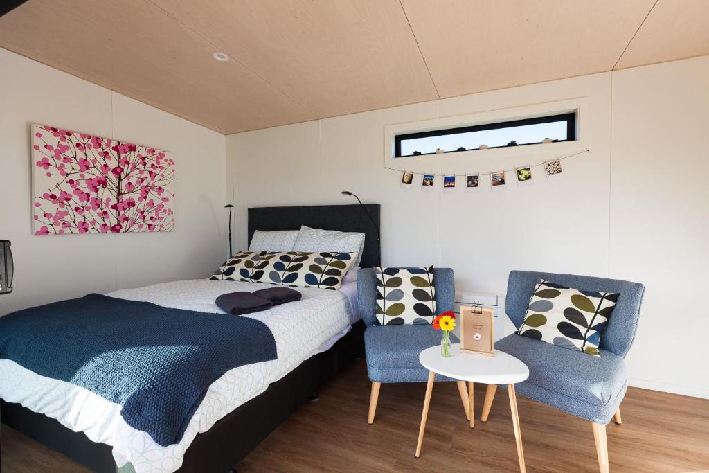 a bedroom with a bed and a table and chairs at Romantic Vineyard getaway in Waipara