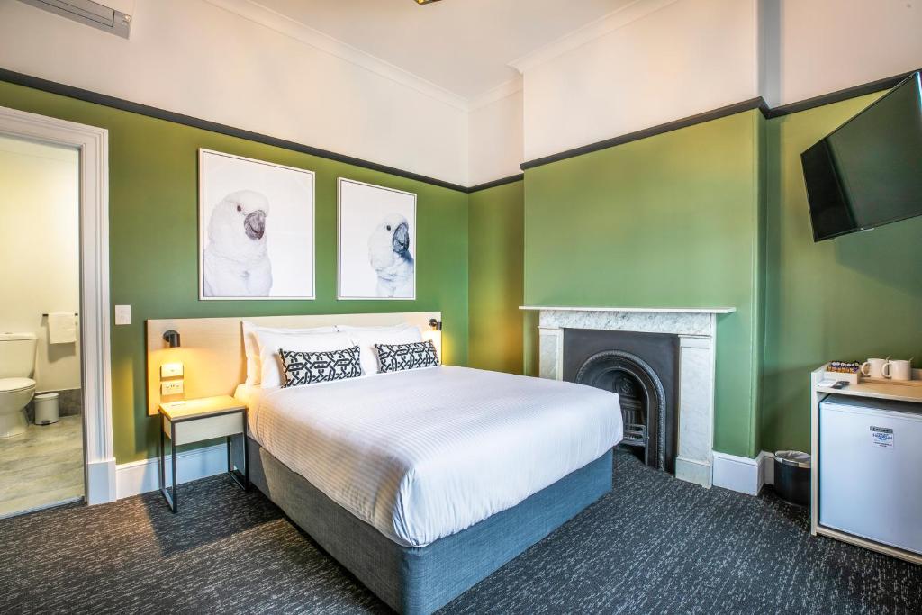 1 dormitorio con paredes verdes y 1 cama con chimenea en Nightcap at Exeter Hotel, en Port Adelaide