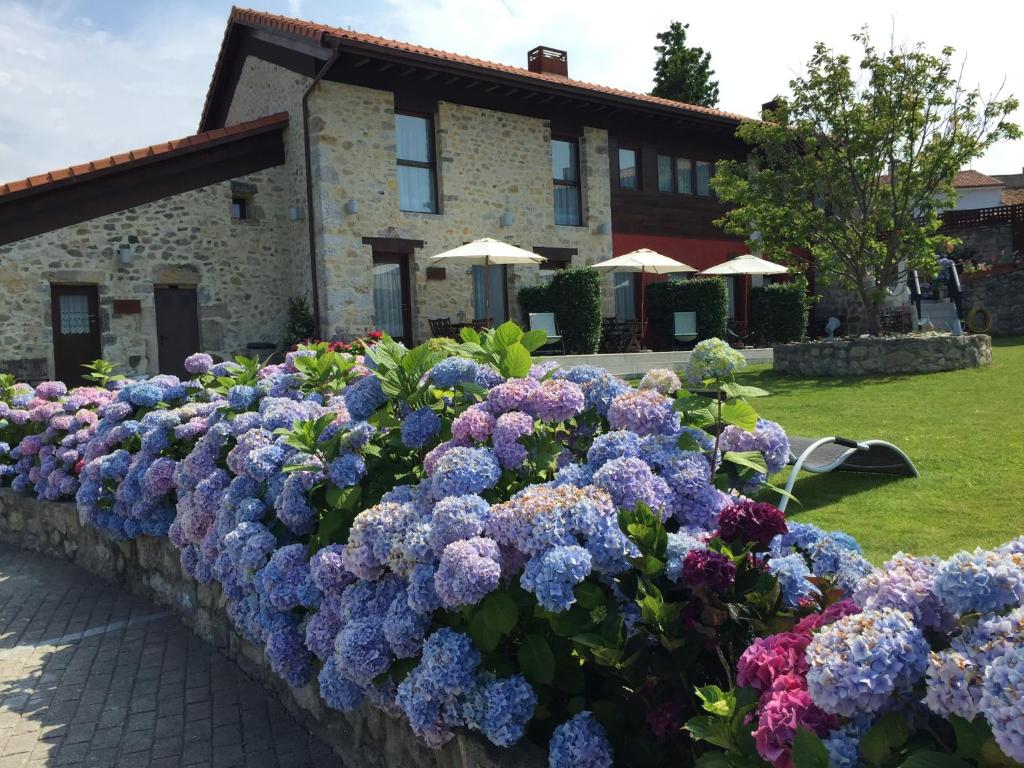 a hedge of purple and blue flowers in front of a building at Apartamentos El Hospital de Villahormes in Villahormes