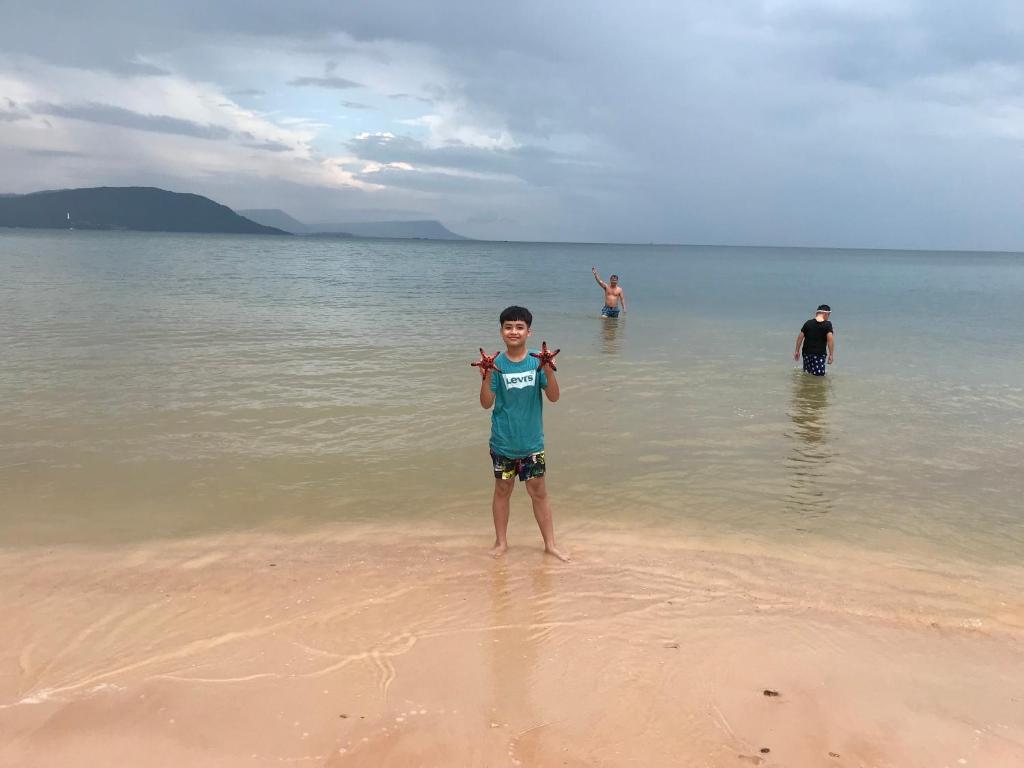 a young boy standing in the water on the beach at An Yen Resort in Phú Quốc