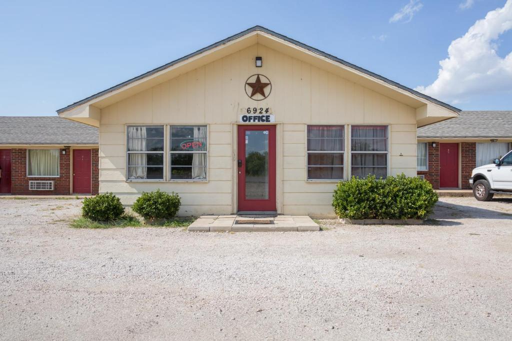 ein Gebäude mit einer roten Tür auf einem Parkplatz in der Unterkunft OYO Hotel Breckenridge TX Hubbard Creek Lake in Breckenridge