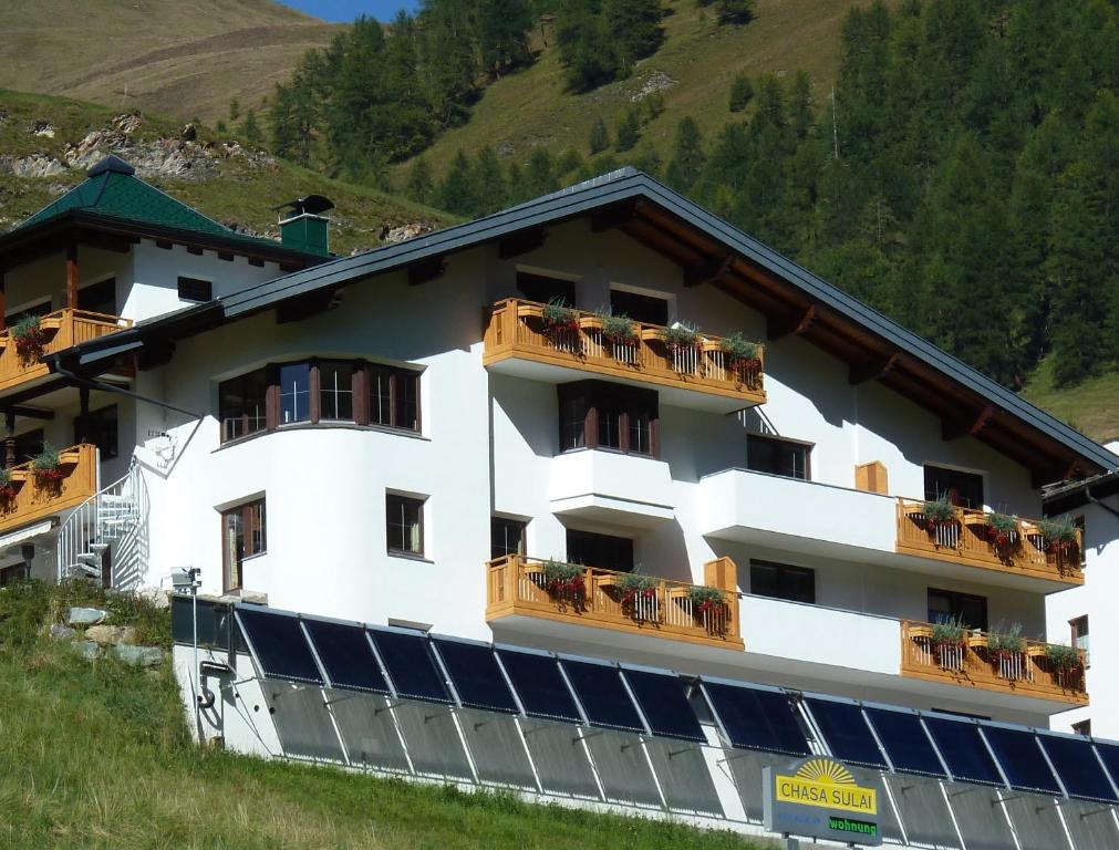 un edificio blanco con balcones y flores. en Chasa Sulai Appartements en Samnaun