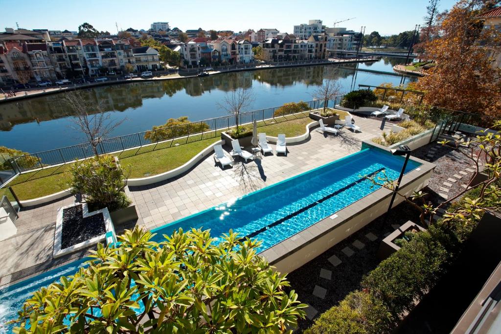 uma piscina ao lado de uma massa de água em East Perth Suites Hotel em Perth