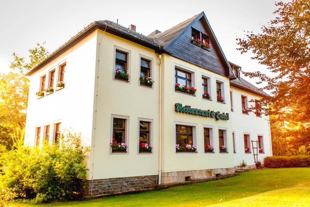 une maison blanche avec des boîtes de fleurs sur les fenêtres dans l'établissement Ferienhotel Augustusburg, à Augustusburg