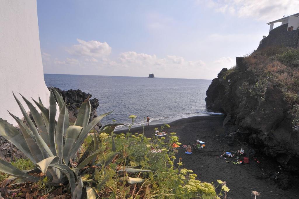 a black beach with people on the sand and the ocean at Hotel Villaggio Stromboli - isola di Stromboli in Stromboli