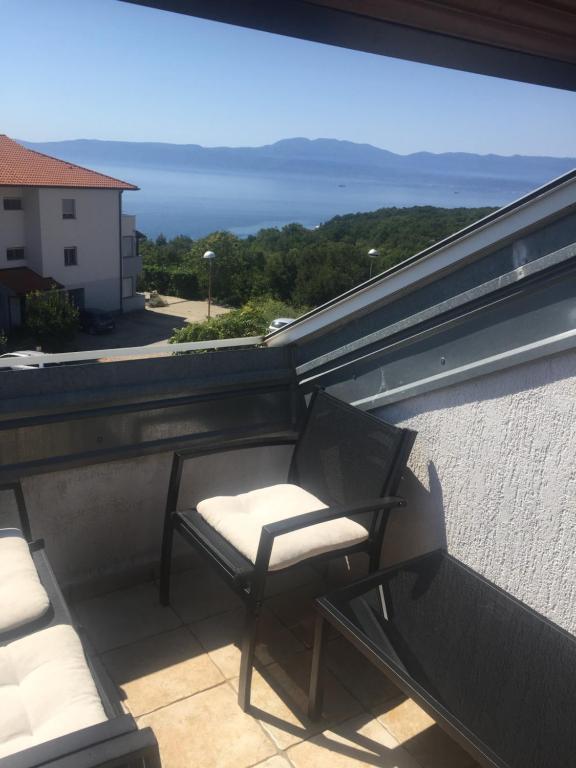 a chair on a balcony with a view of the ocean at Apartment Doderovic in Kostrena